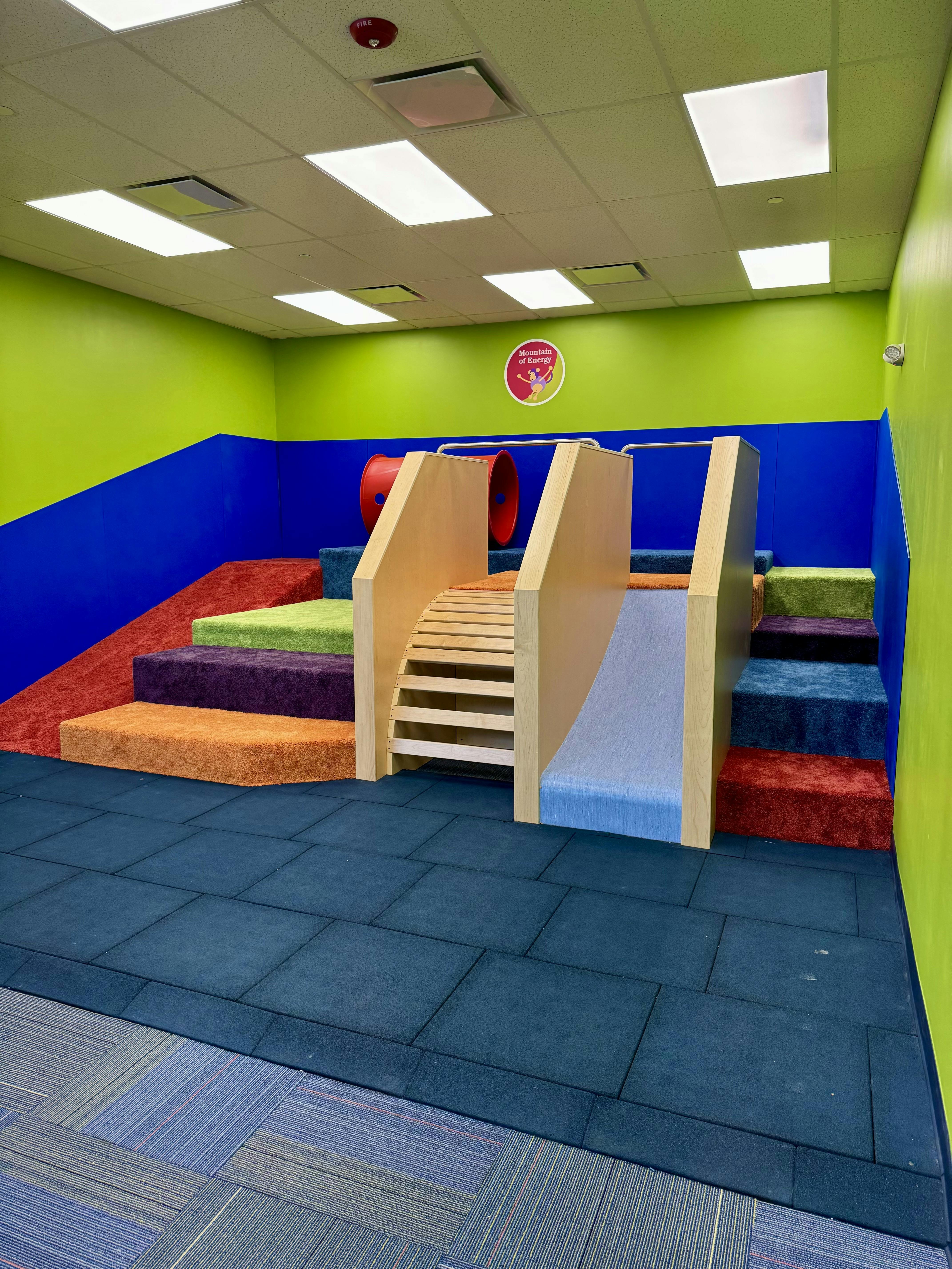Colorful indoor play area with steps, slide, and tunnel