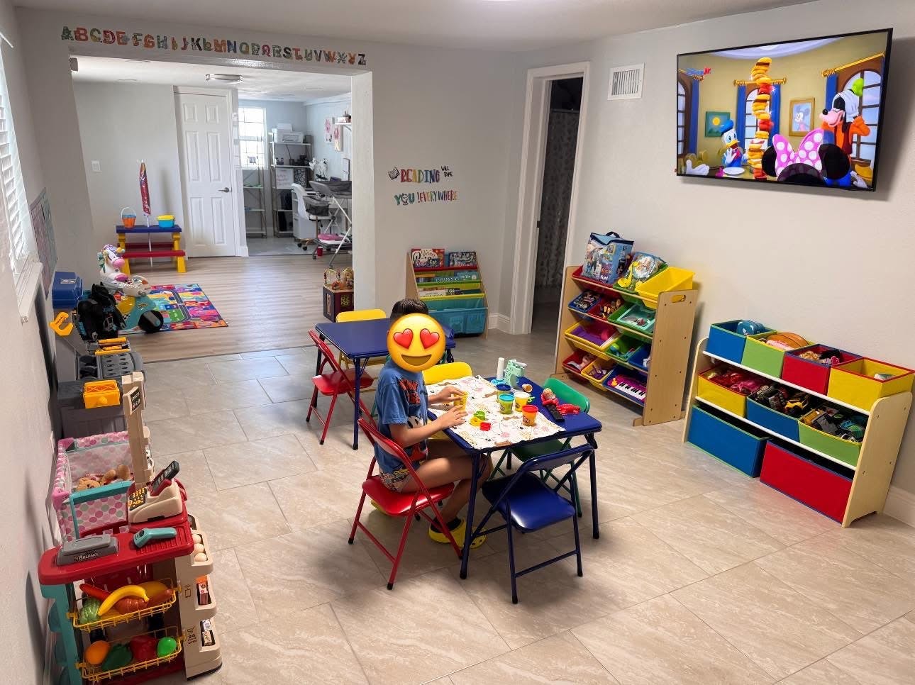 Child sitting at a small table with toys in a playroom