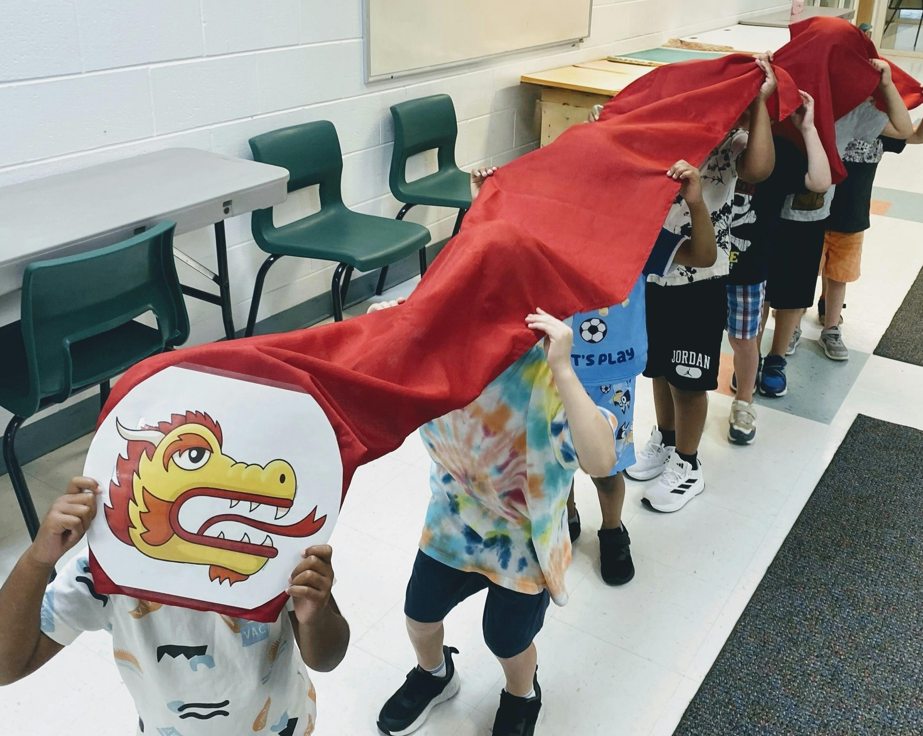 Group of children holding up a long red dragon costume in a line