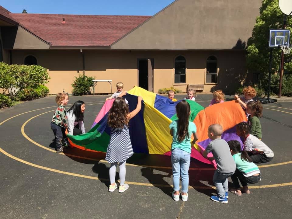 Children playing with a colorful parachute outdoors