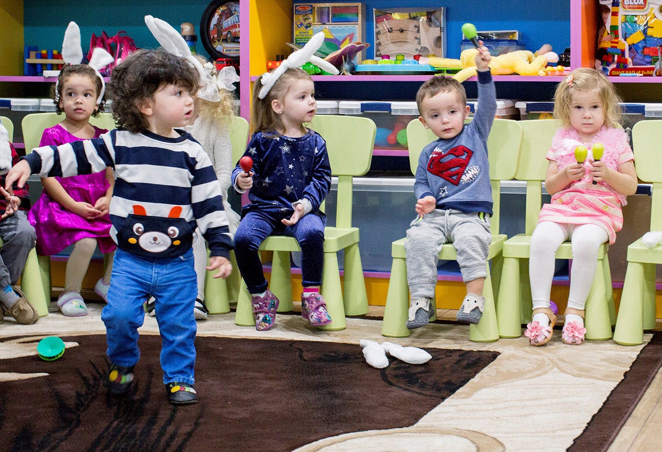 Children in bunny ears playing in a classroom
