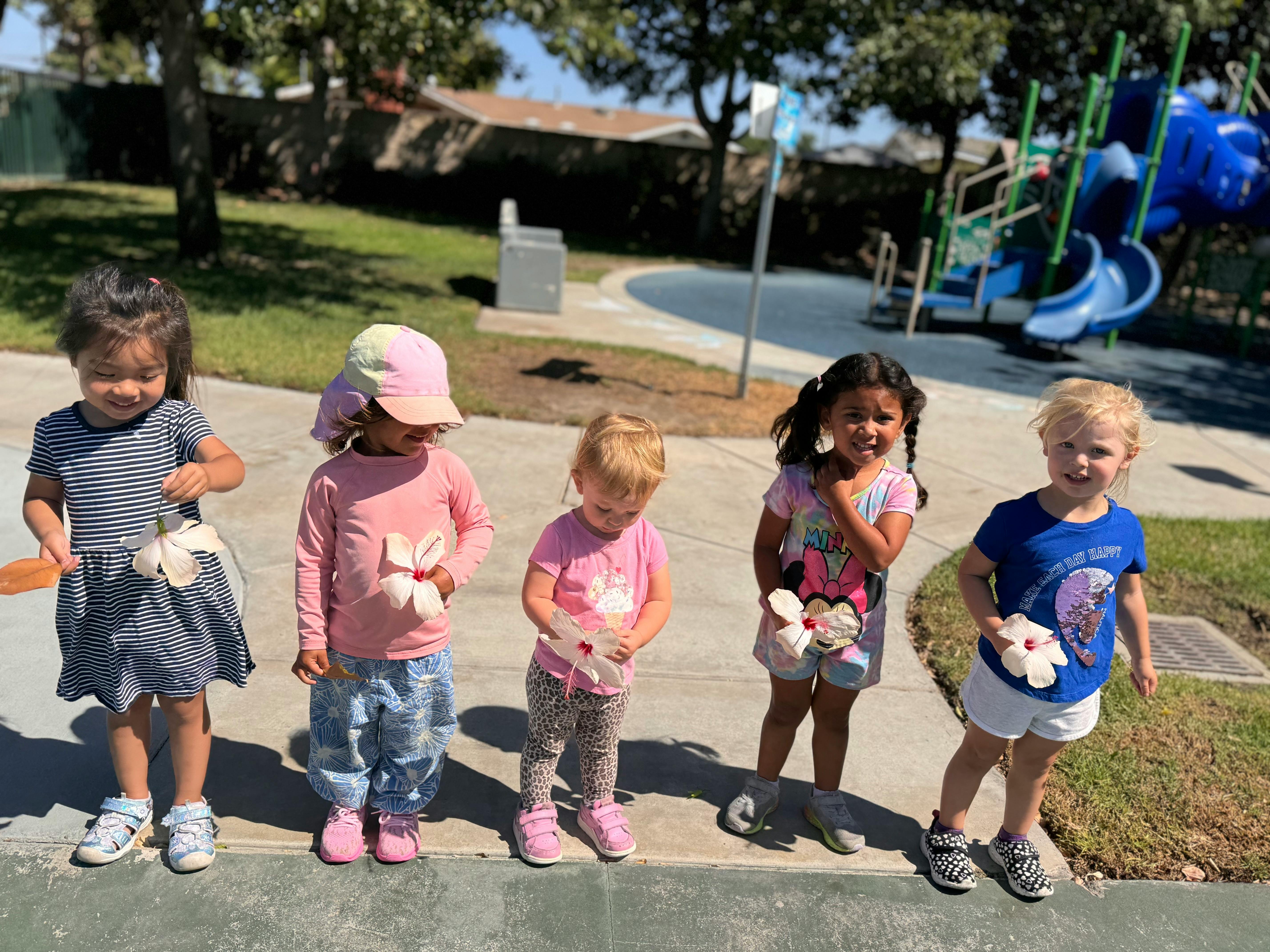 Five children standing outdoors holding small white objects