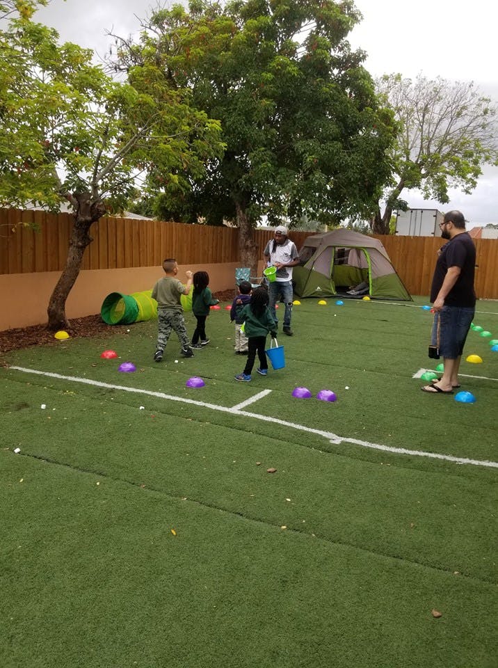 Adults and children on a grassy area with a tent and play tunnel