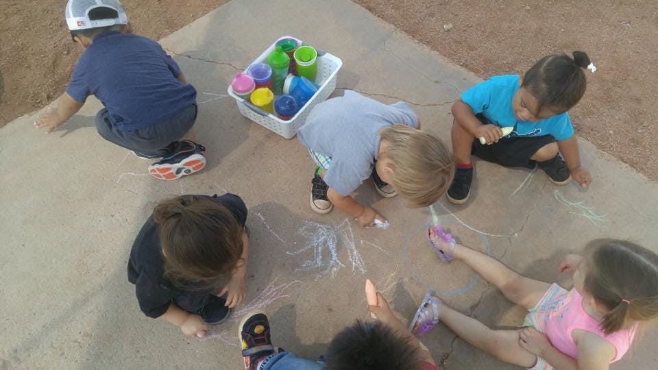 Children drawing with chalk on pavement