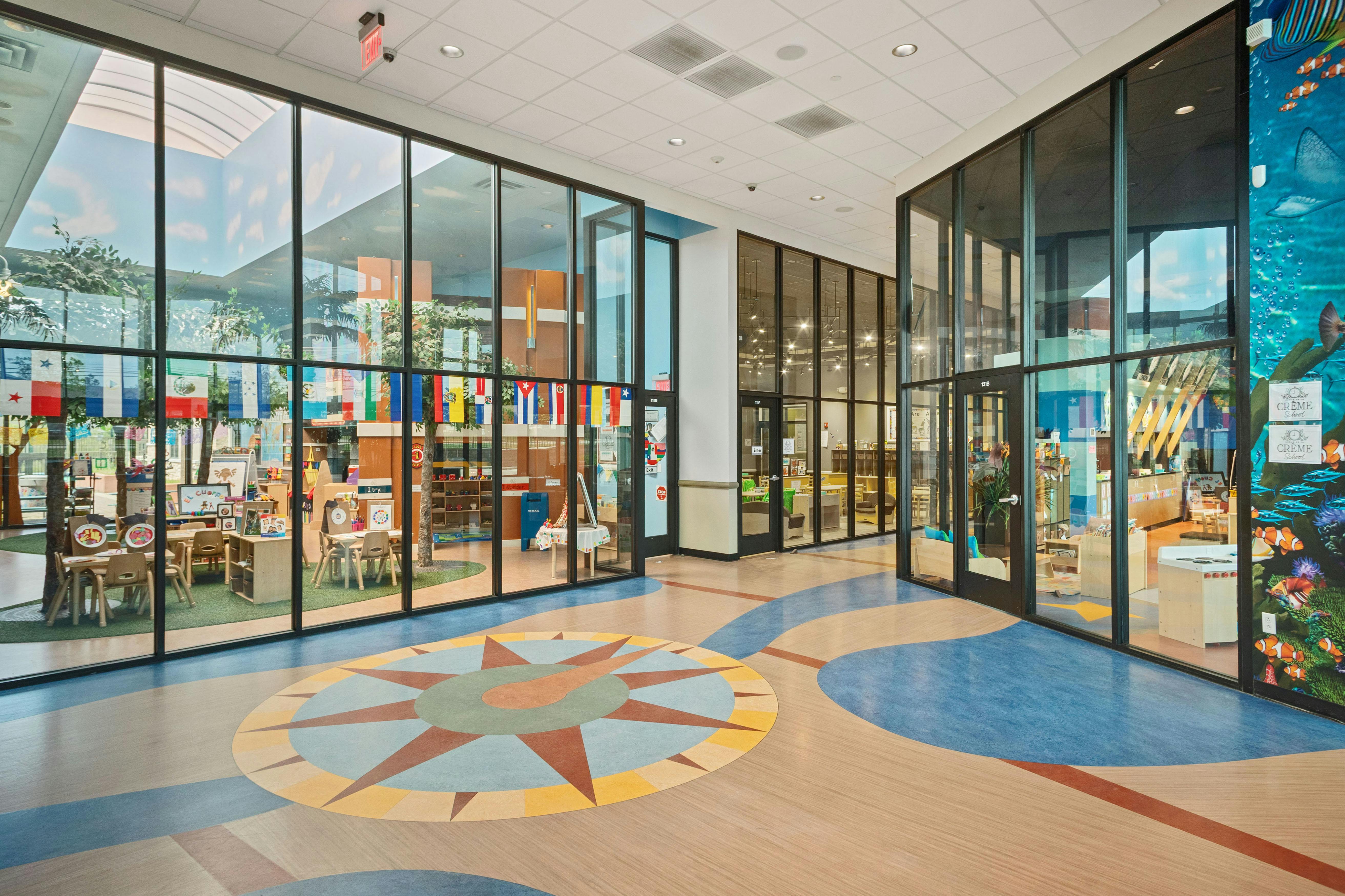 Lobby with compass design on floor and classrooms visible through large glass windows