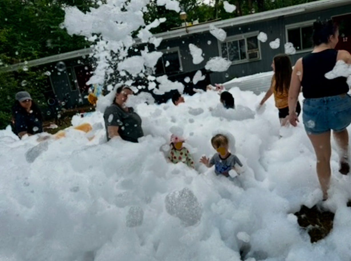 People and children playing in a yard filled with foam