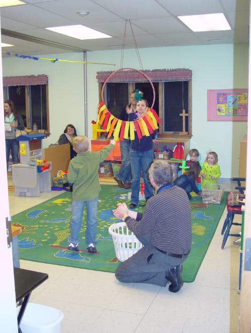 People and children playing with a hoop and basket in a room