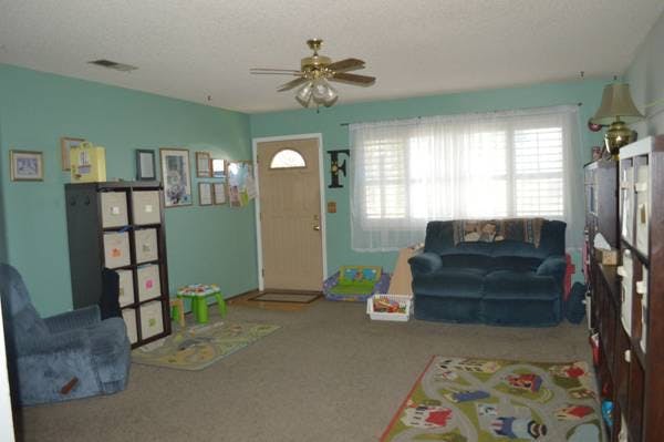 Living room with a blue sofa, a ceiling fan, and a door