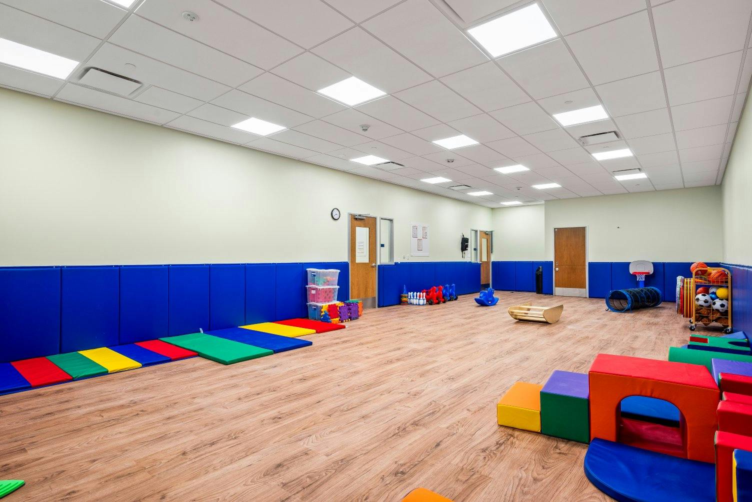 Playroom with soft floor mats, toys, and padded blue walls