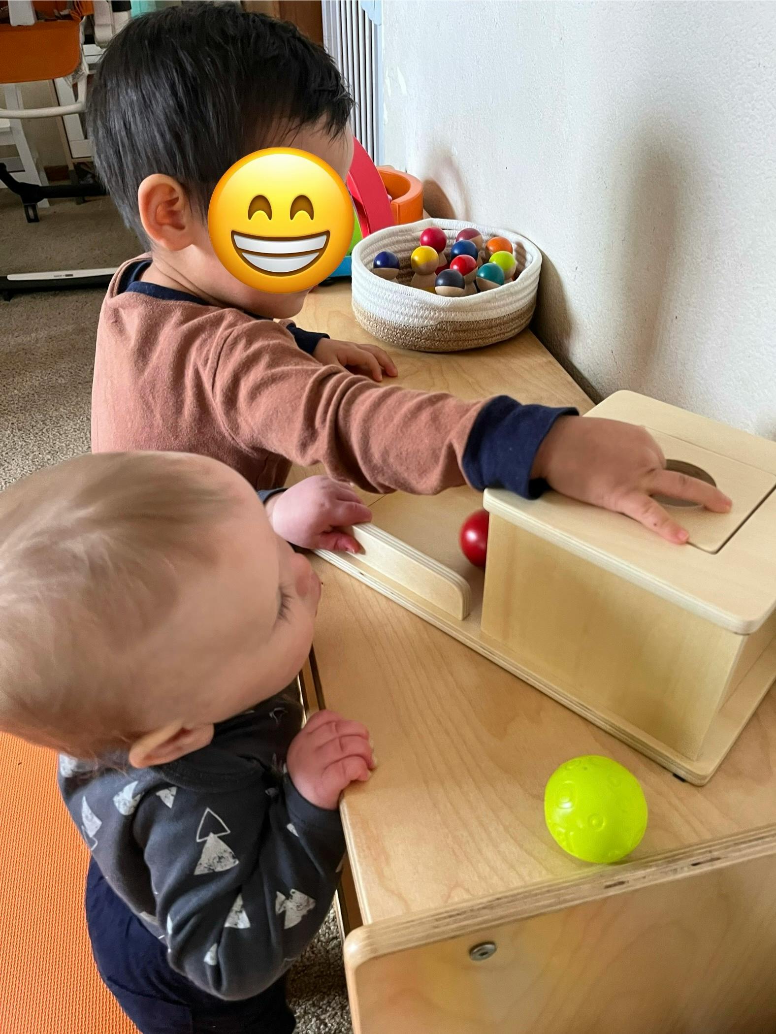 Two children playing with wooden toys and colorful balls