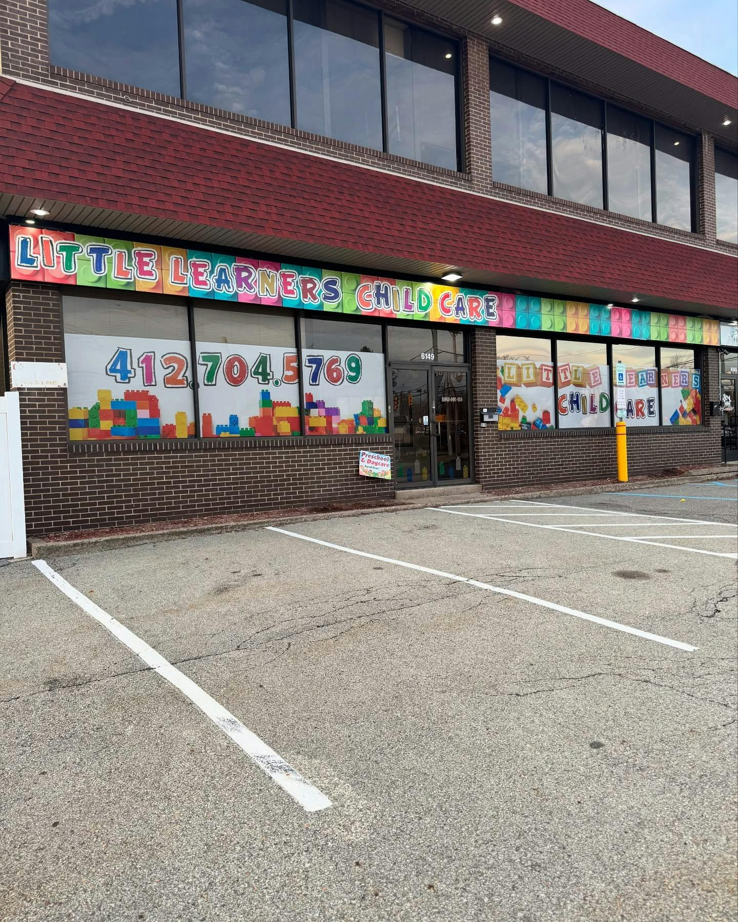 Little Learners Child Care sign on a brick building with parking spaces