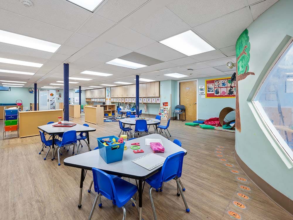Classroom with small tables and chairs, and play areas
