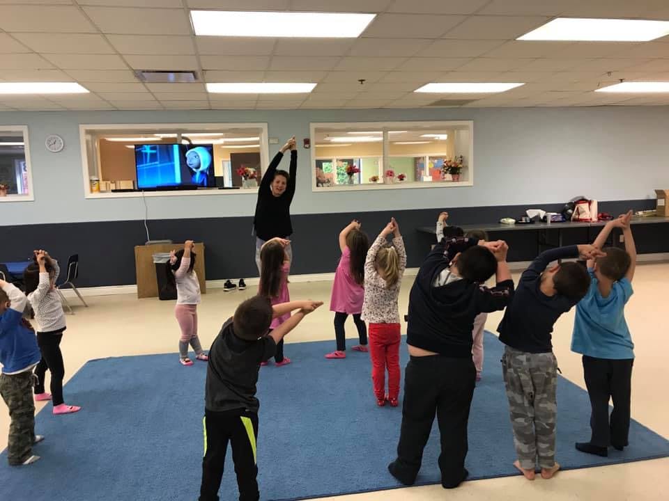 Adult and children stretching in a room