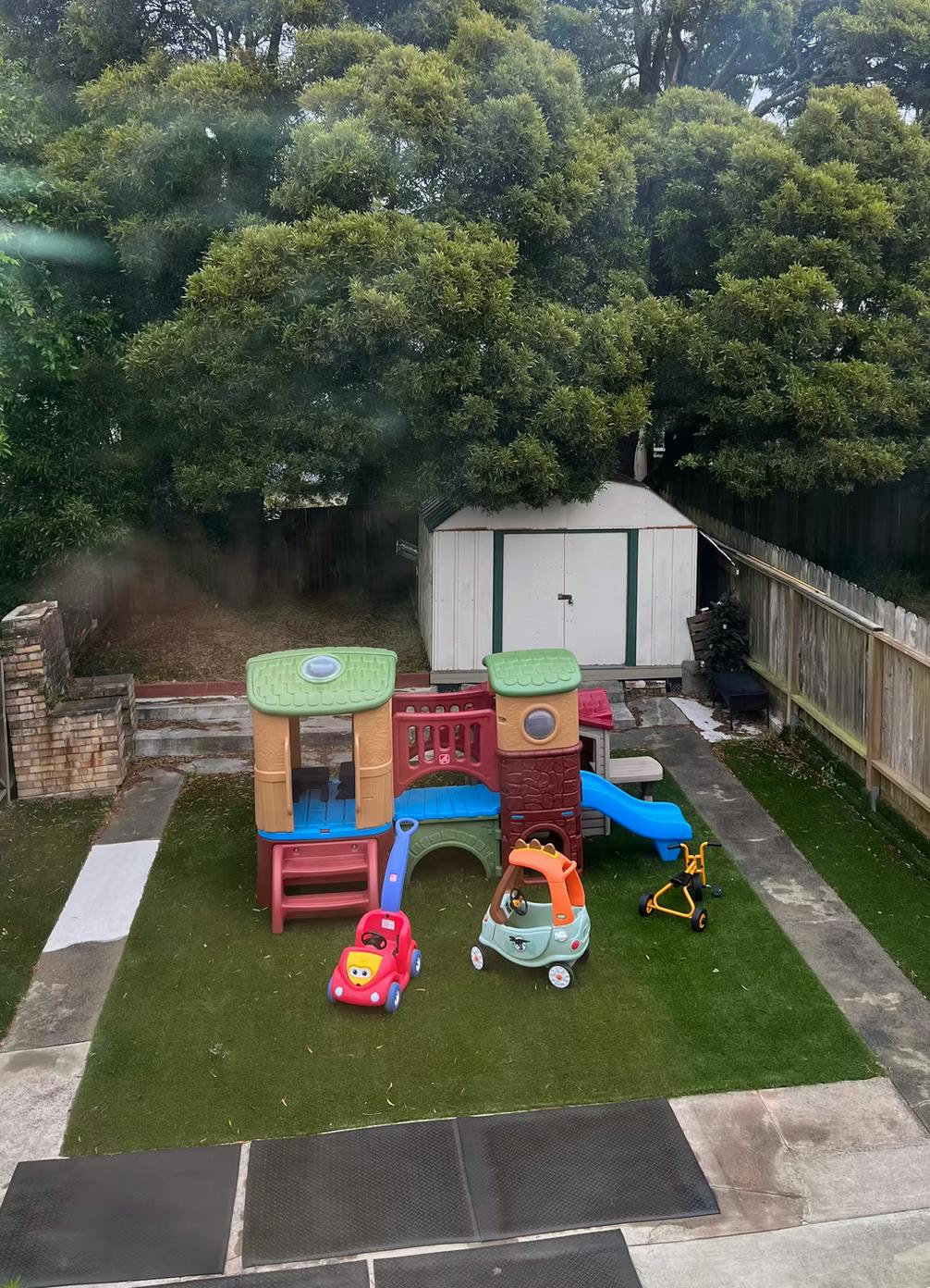 Children's play structure with slide and toy cars on artificial grass