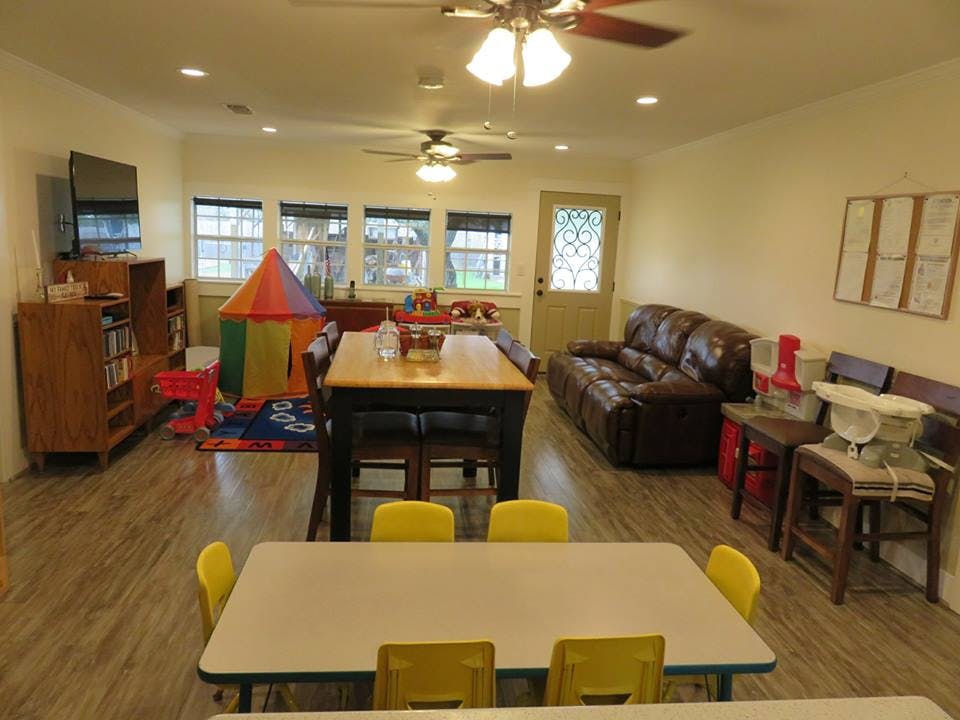 Playroom with tables, chairs, sofa, and play tent