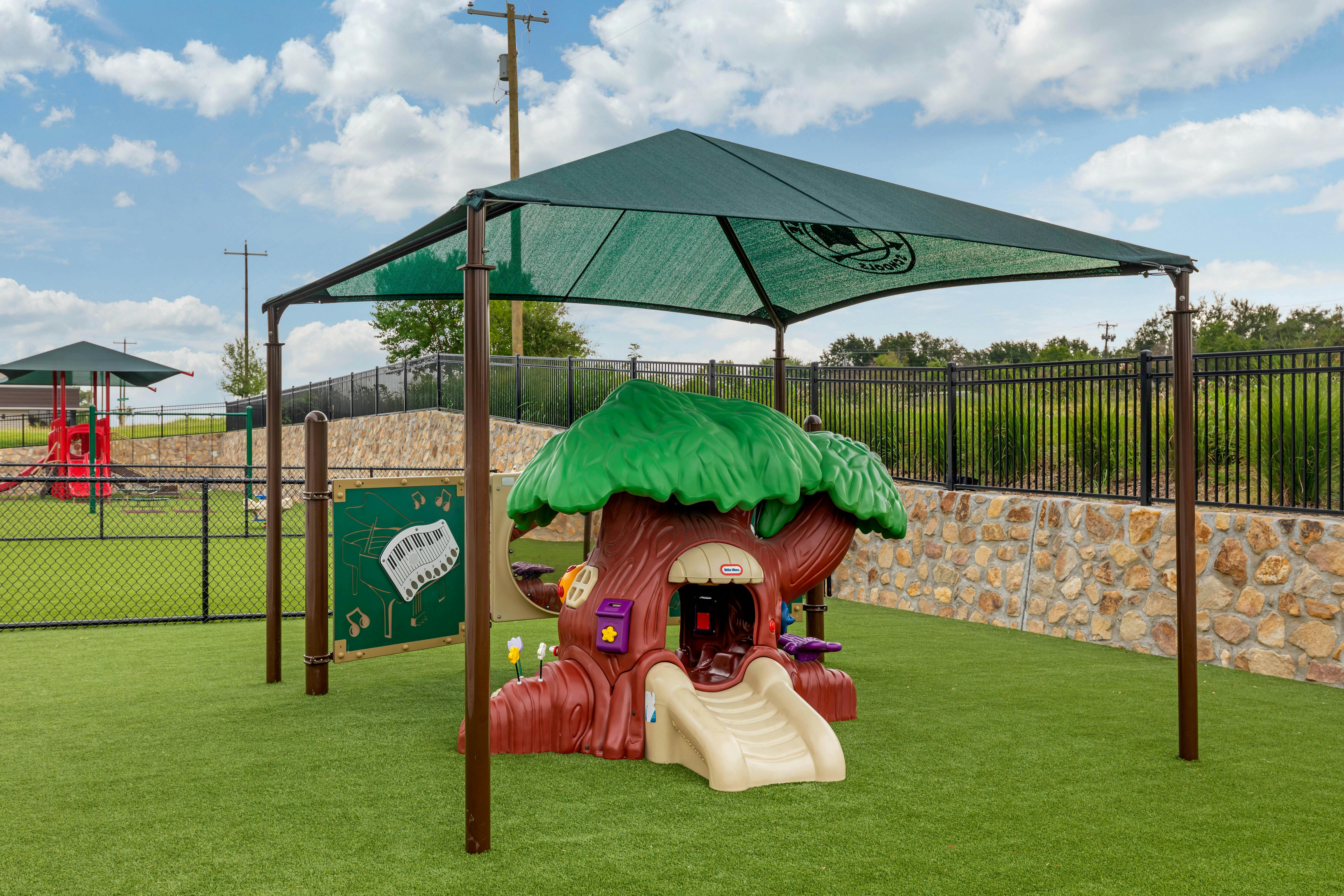 Playground with a treehouse-shaped slide and a piano-themed activity board