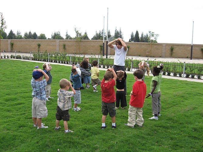 Person leading a group of children in an outdoor activity