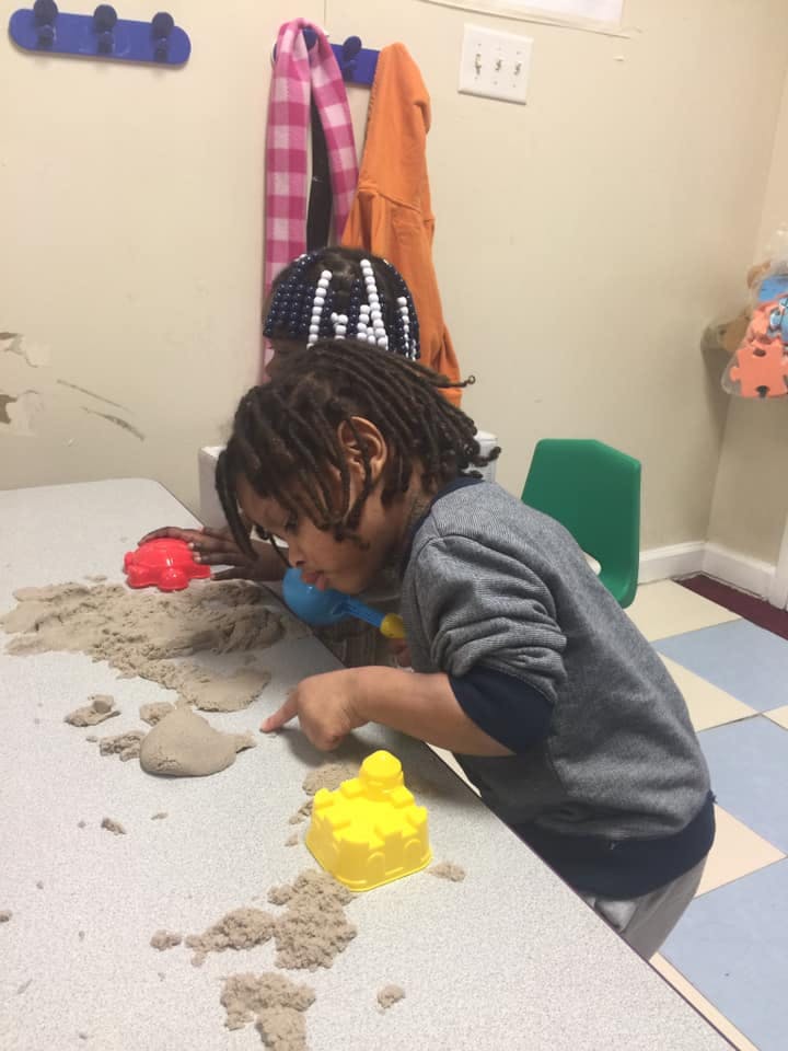 Child playing with kinetic sand on a table