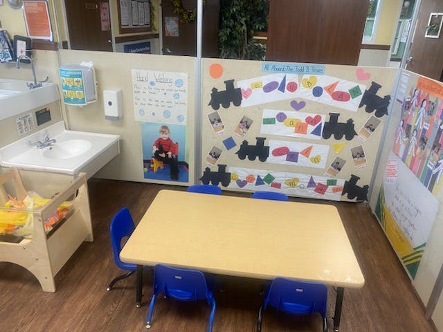 Classroom with child-sized table and chairs, sinks, and wall decorations
