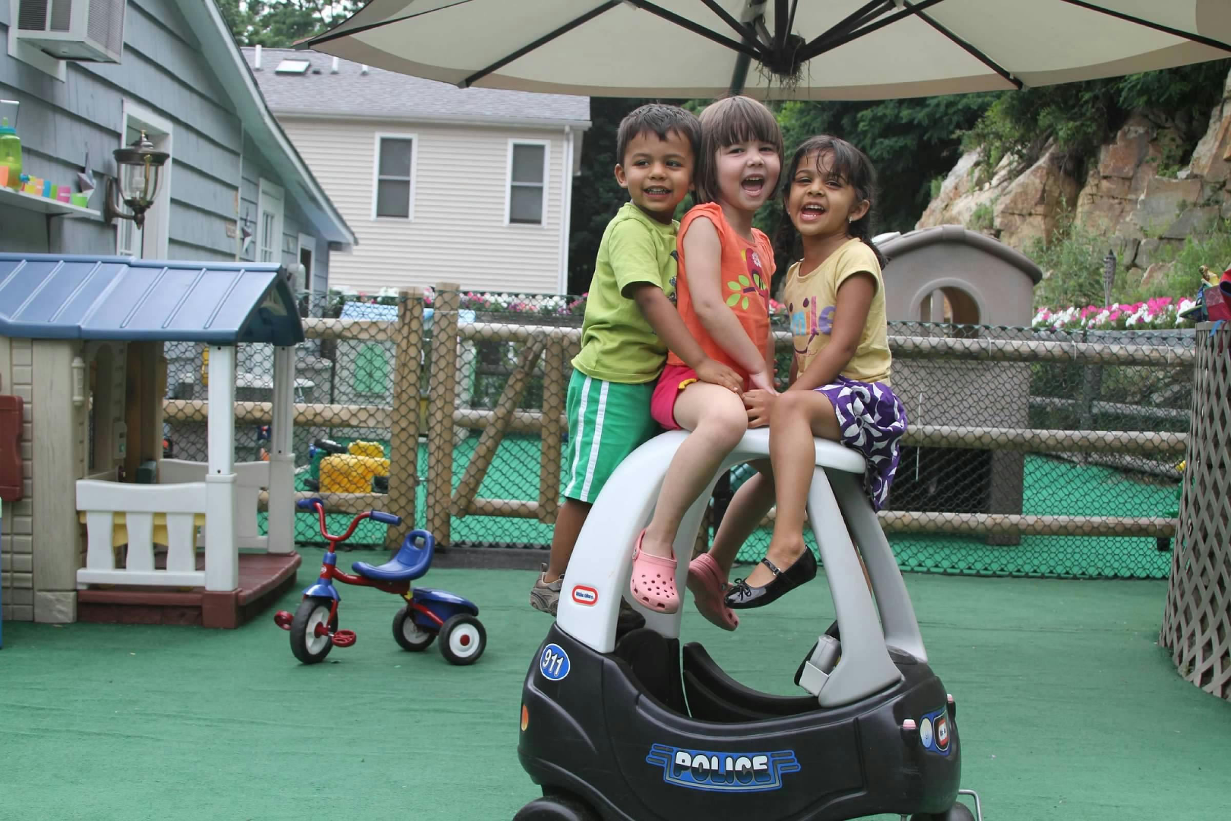 Three children on a toy car on a playground