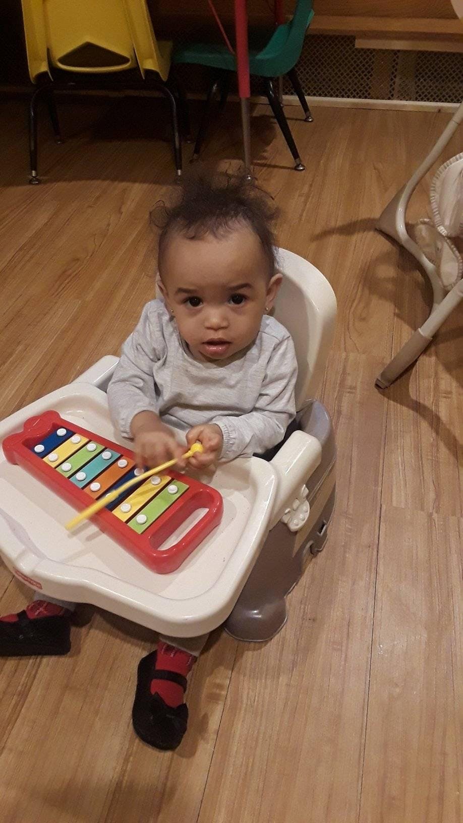 Child in a high chair playing with a toy xylophone