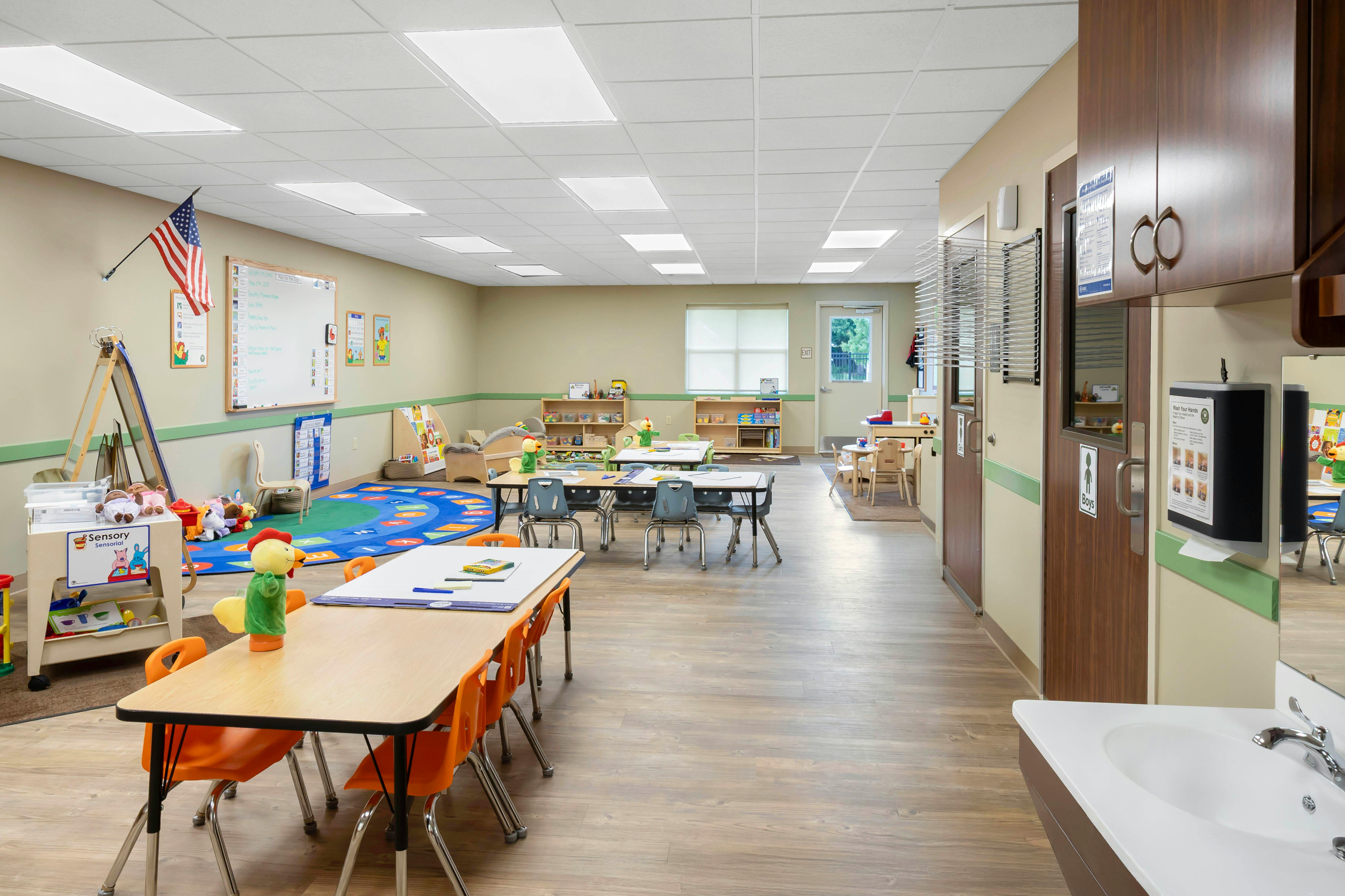 An empty early childhood classroom with multiple tables and play areas