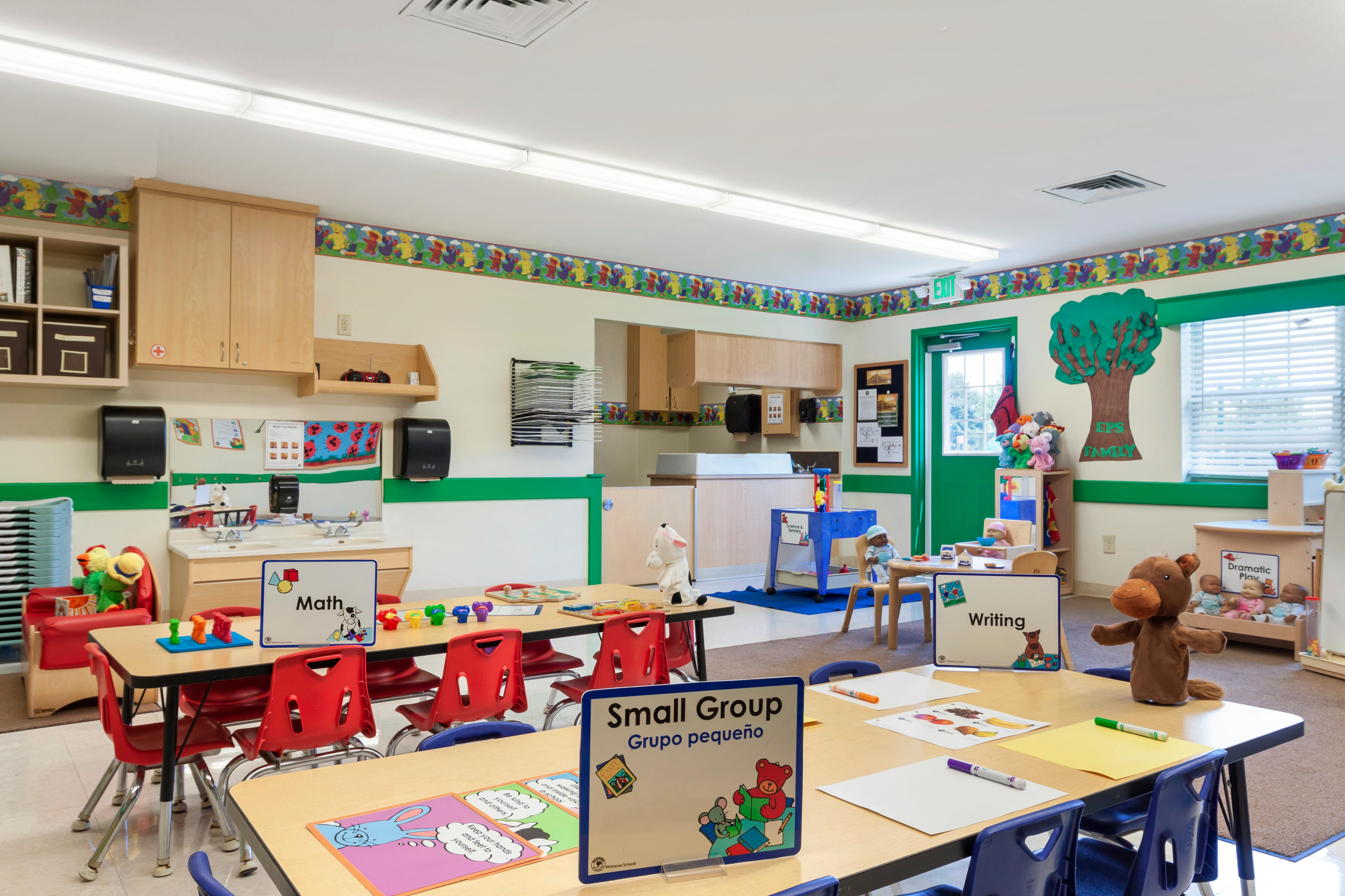 Classroom with small tables and chairs, activity stations, and a changing table