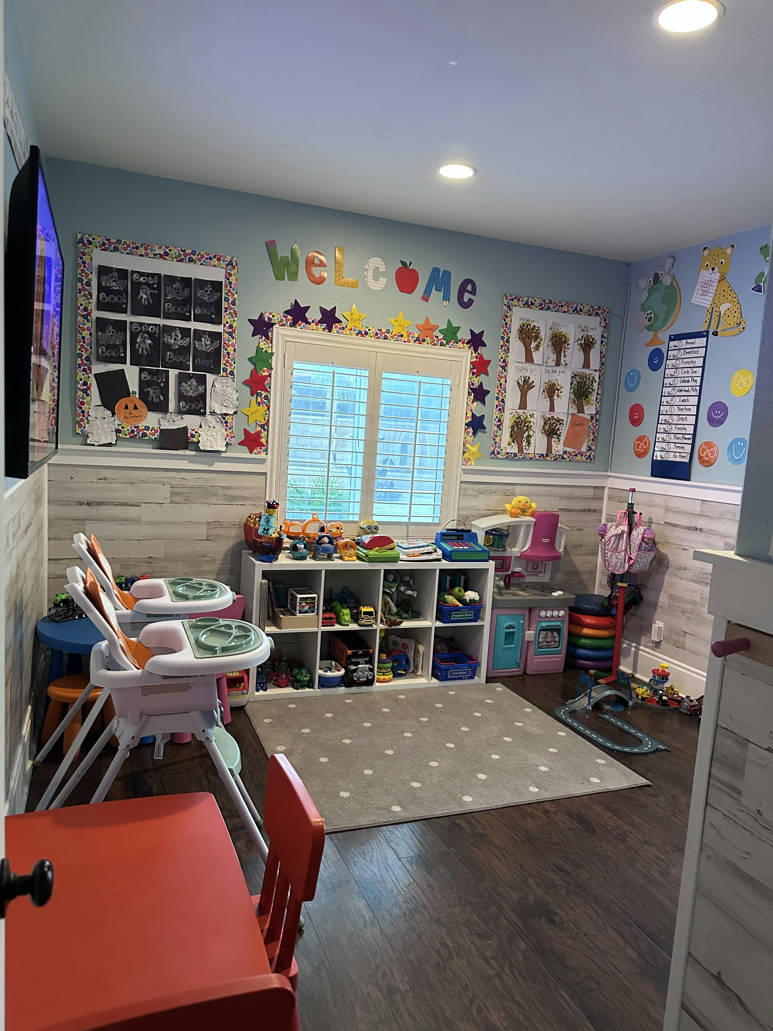 Playroom with children's high chairs, storage shelves, and toy kitchen