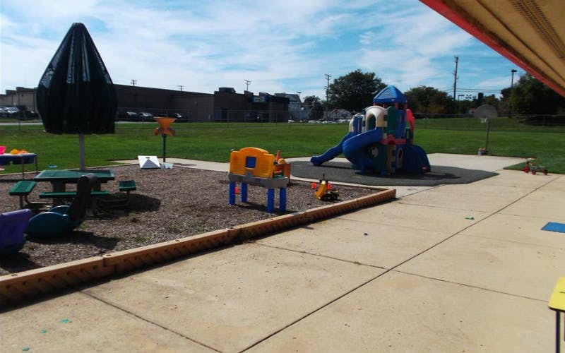 Outdoor playground with a picnic table, play structure, and green grass