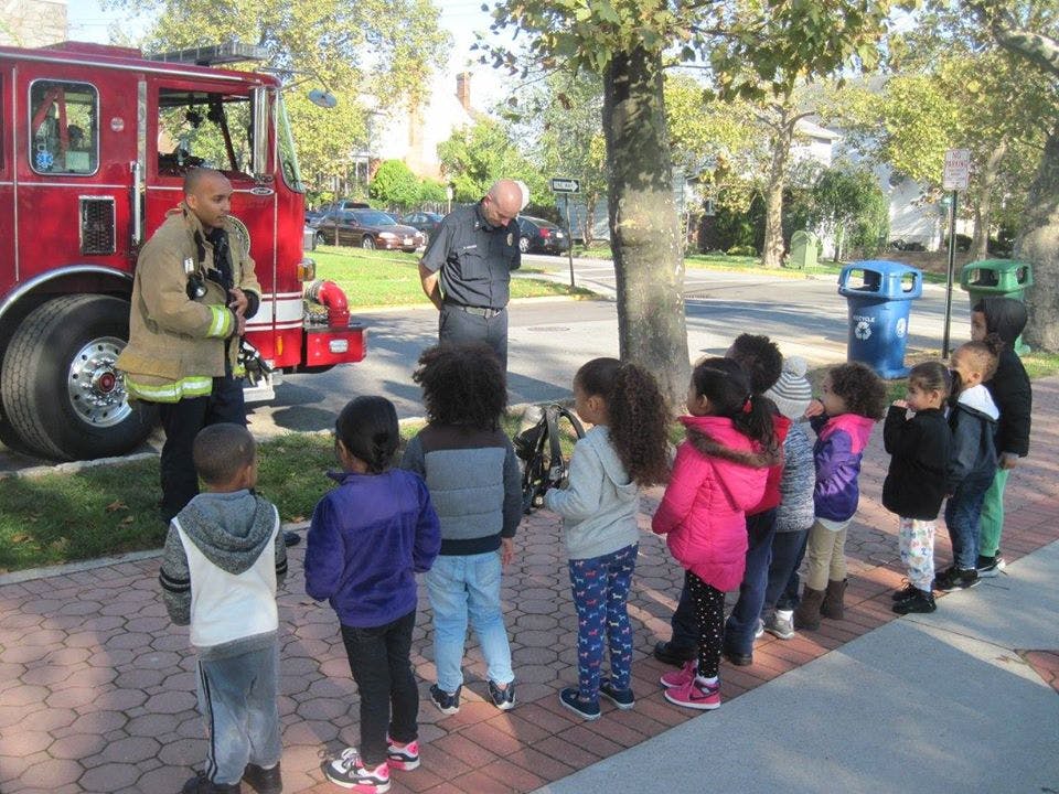 Firefighter and another person talking to a group of children next to a fire truck