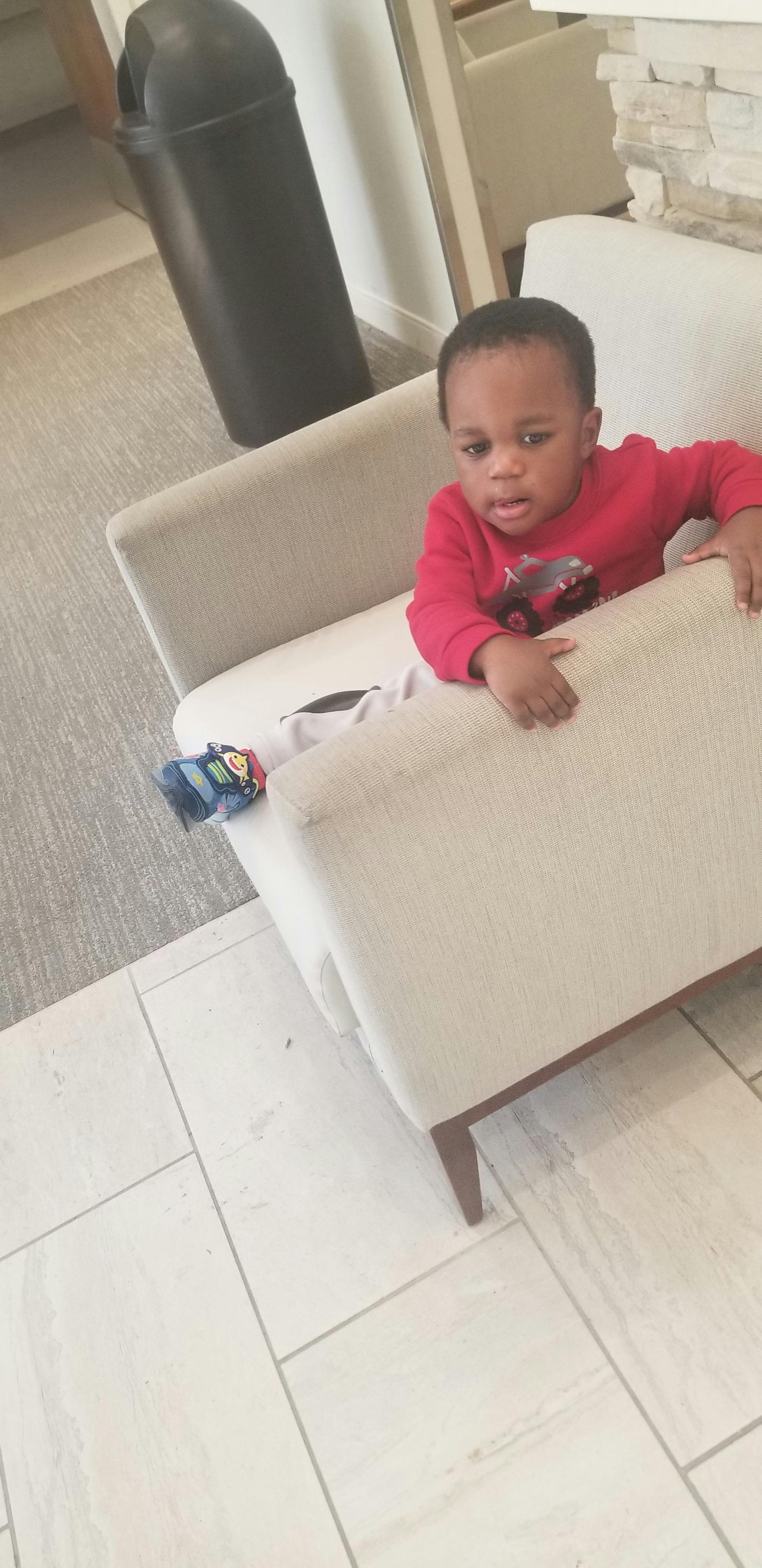 Child in a red shirt sitting on a light-colored couch