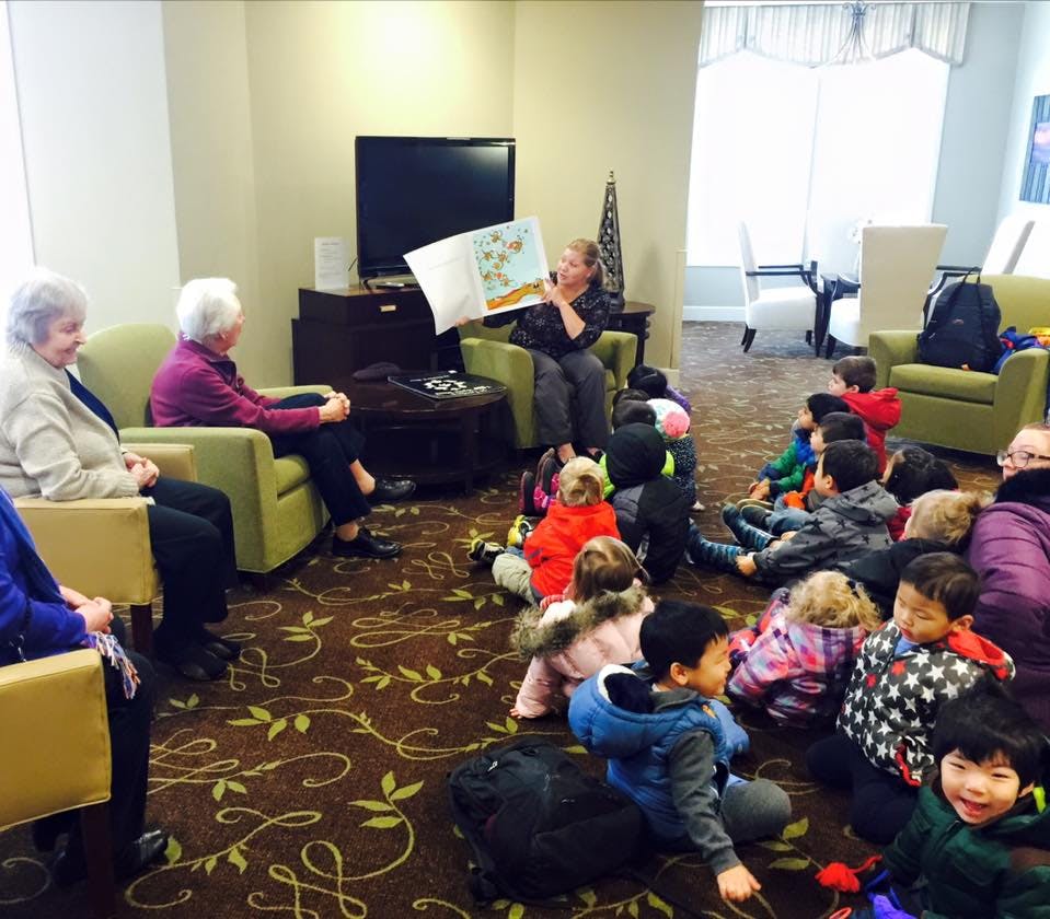 Person reading a book to a group of children and adults