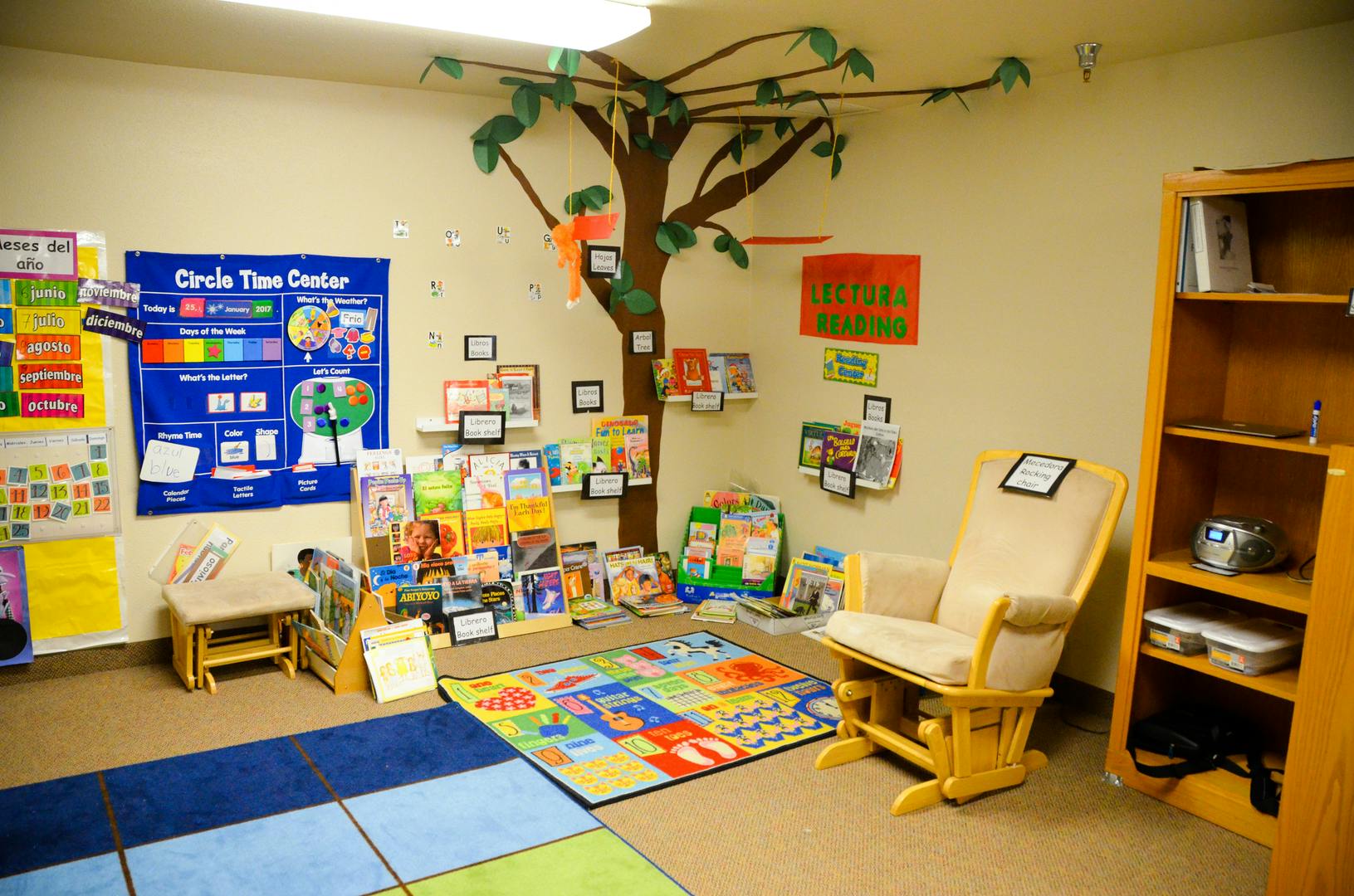 Children's classroom with a tree mural, books, and a rocking chair