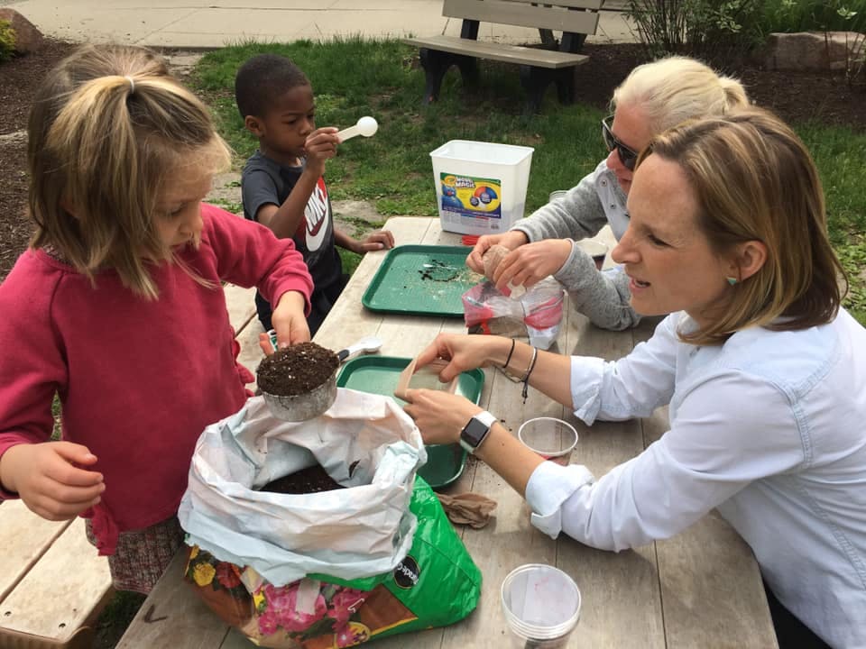Adults and children at a table doing a planting activity