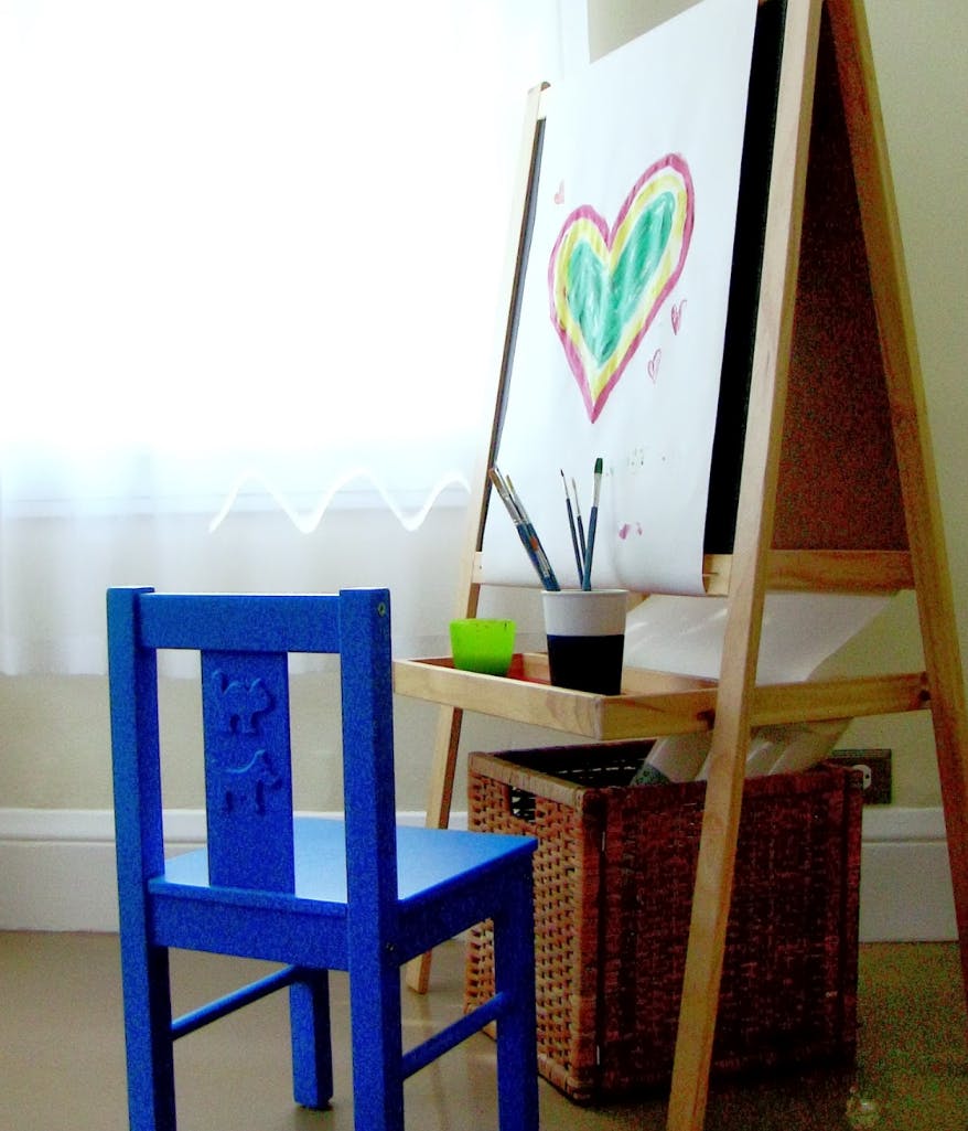 Blue chair next to an easel with a heart drawing