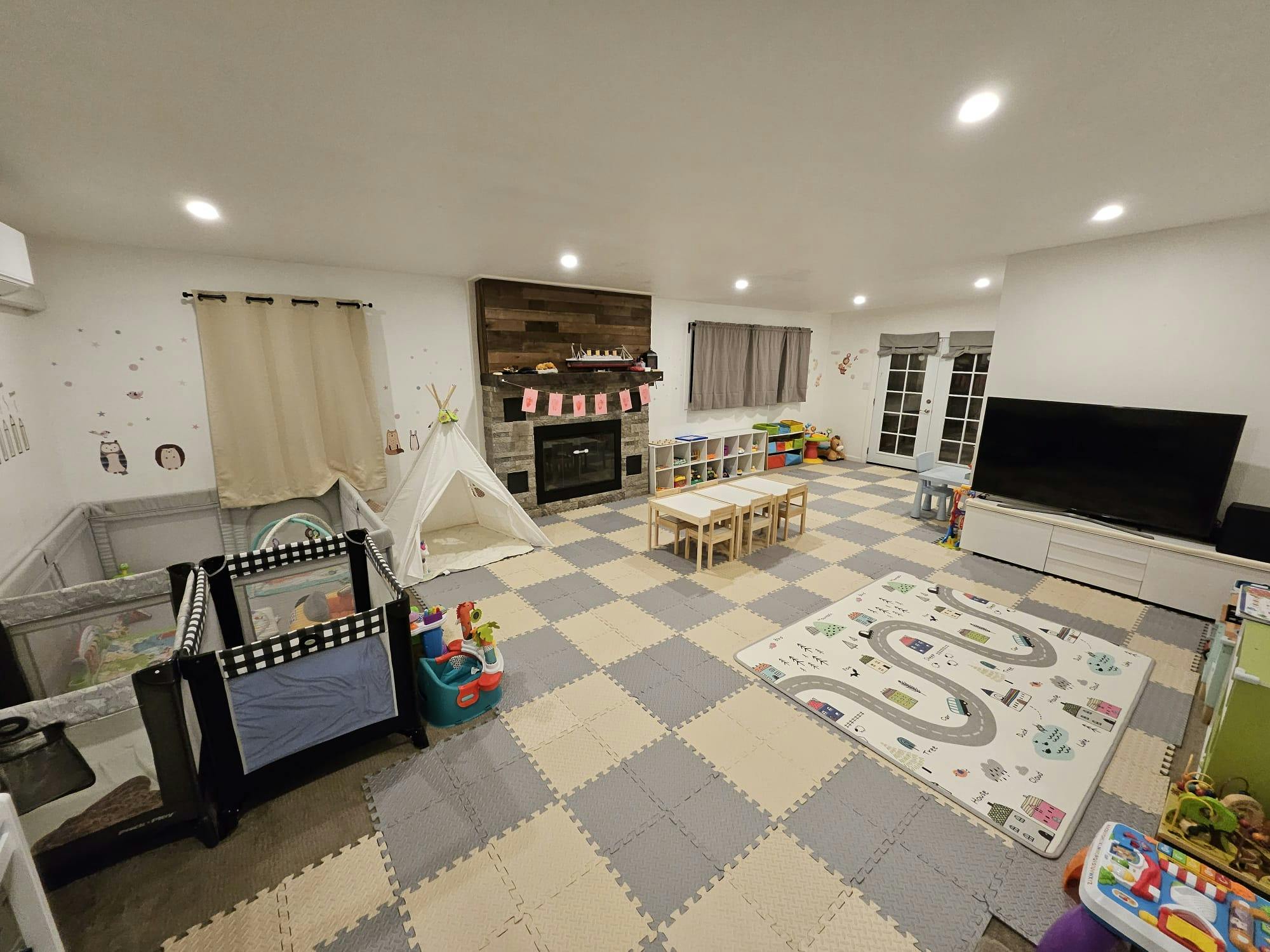 Playroom with cribs, play tent, small table and chairs, and checkered floor