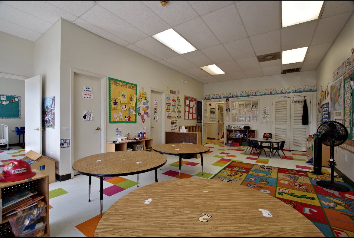 Empty classroom with small tables and colorful rug