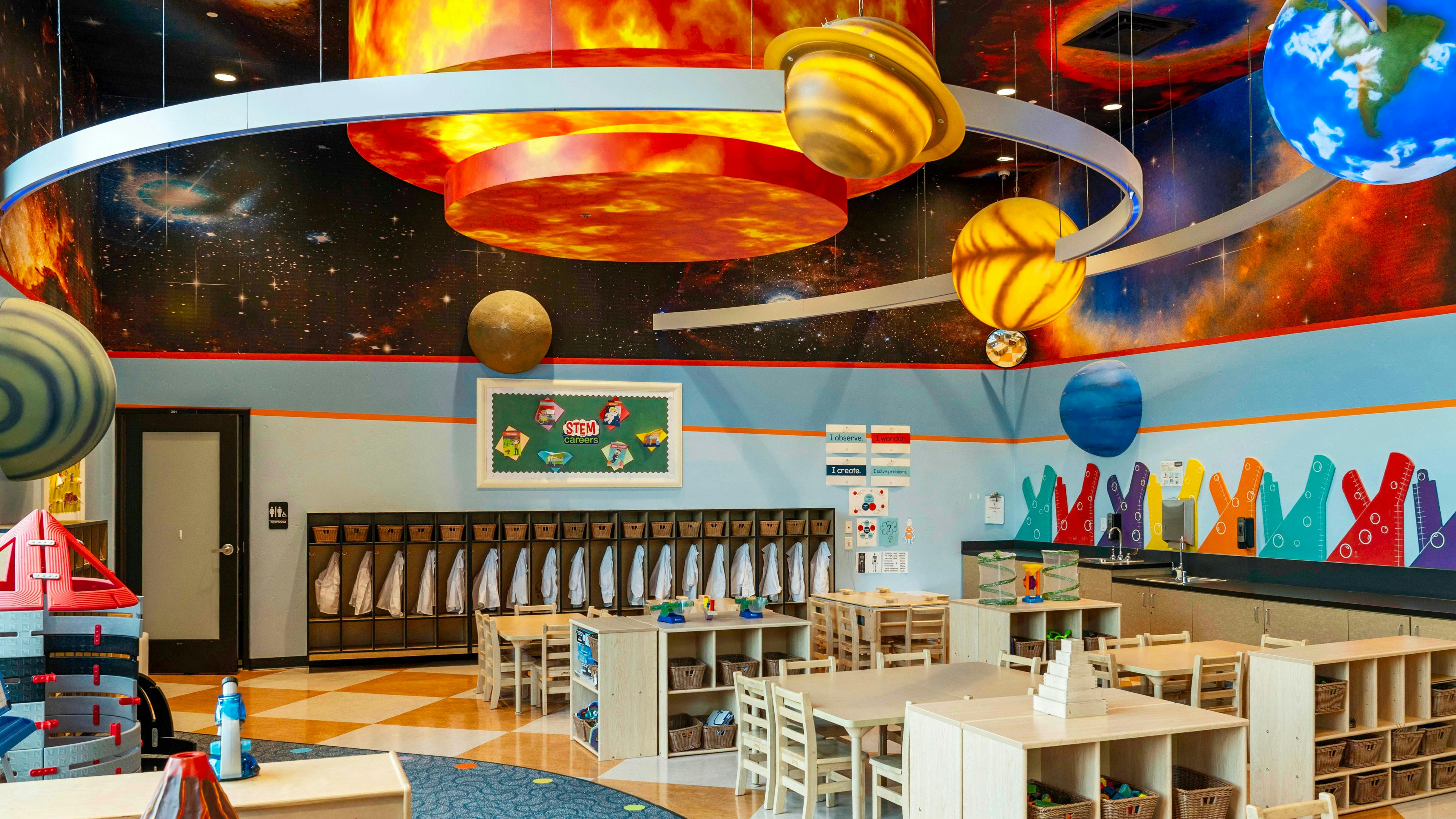 Classroom decorated with planets and space, with small tables and chairs