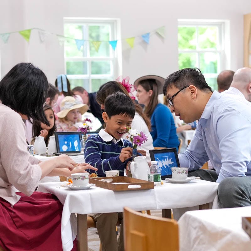 Child smiling and holding flowers with people at a table