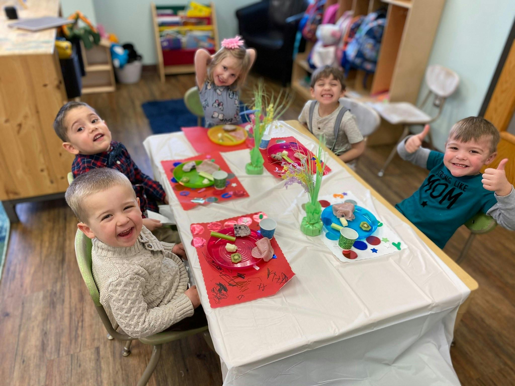 Five children sitting around a table with craft supplies