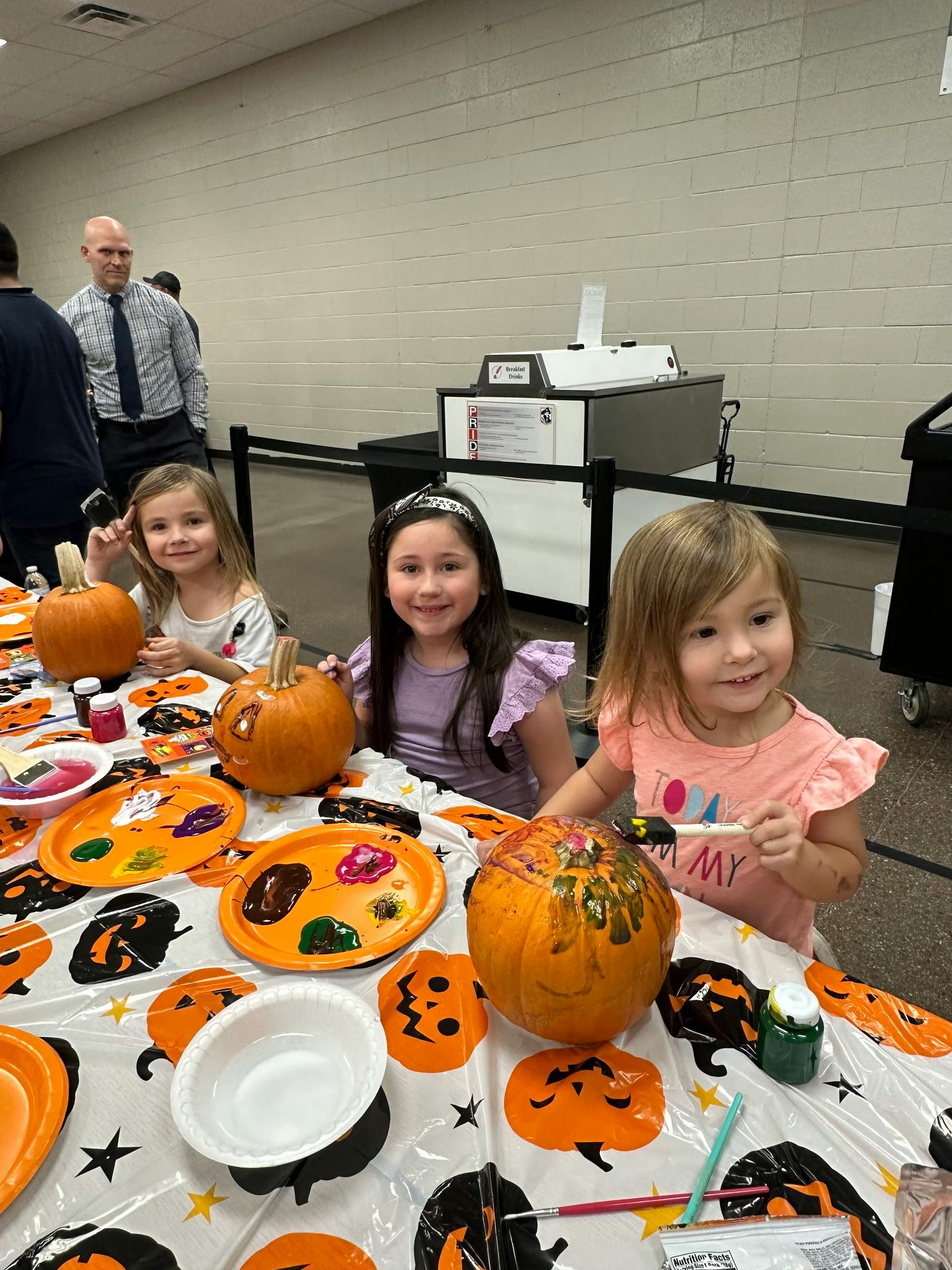 Three children painting pumpkins at a table