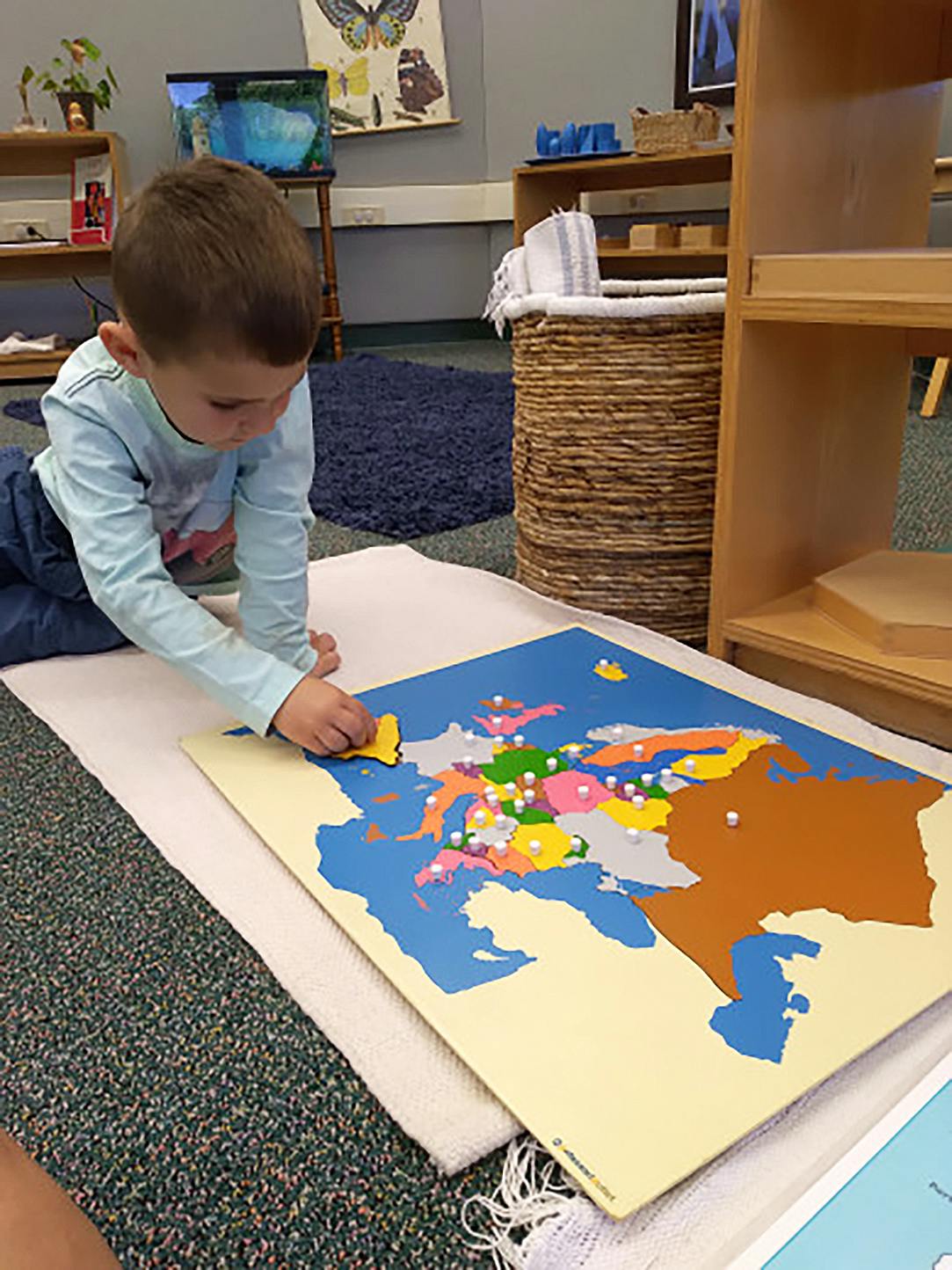 Child playing with a colorful map puzzle on the floor