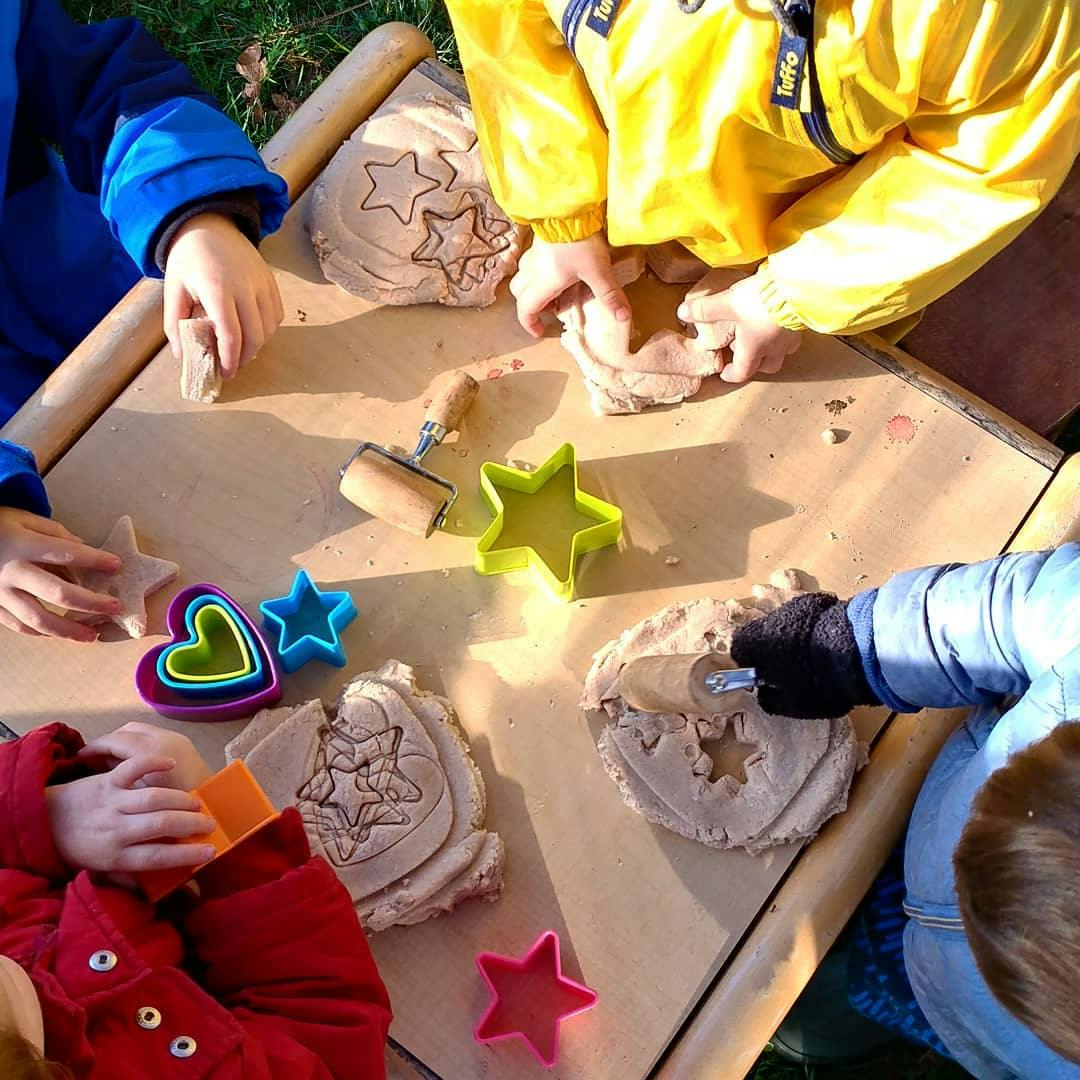 Children playing with dough and cookie cutters on a table