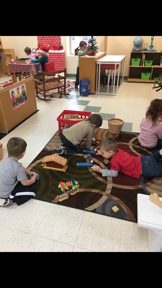 Children playing with toys on a rug in a classroom