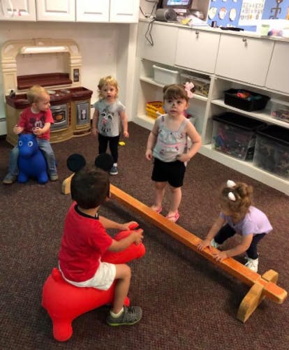 Children playing in a classroom with toys and a balance beam