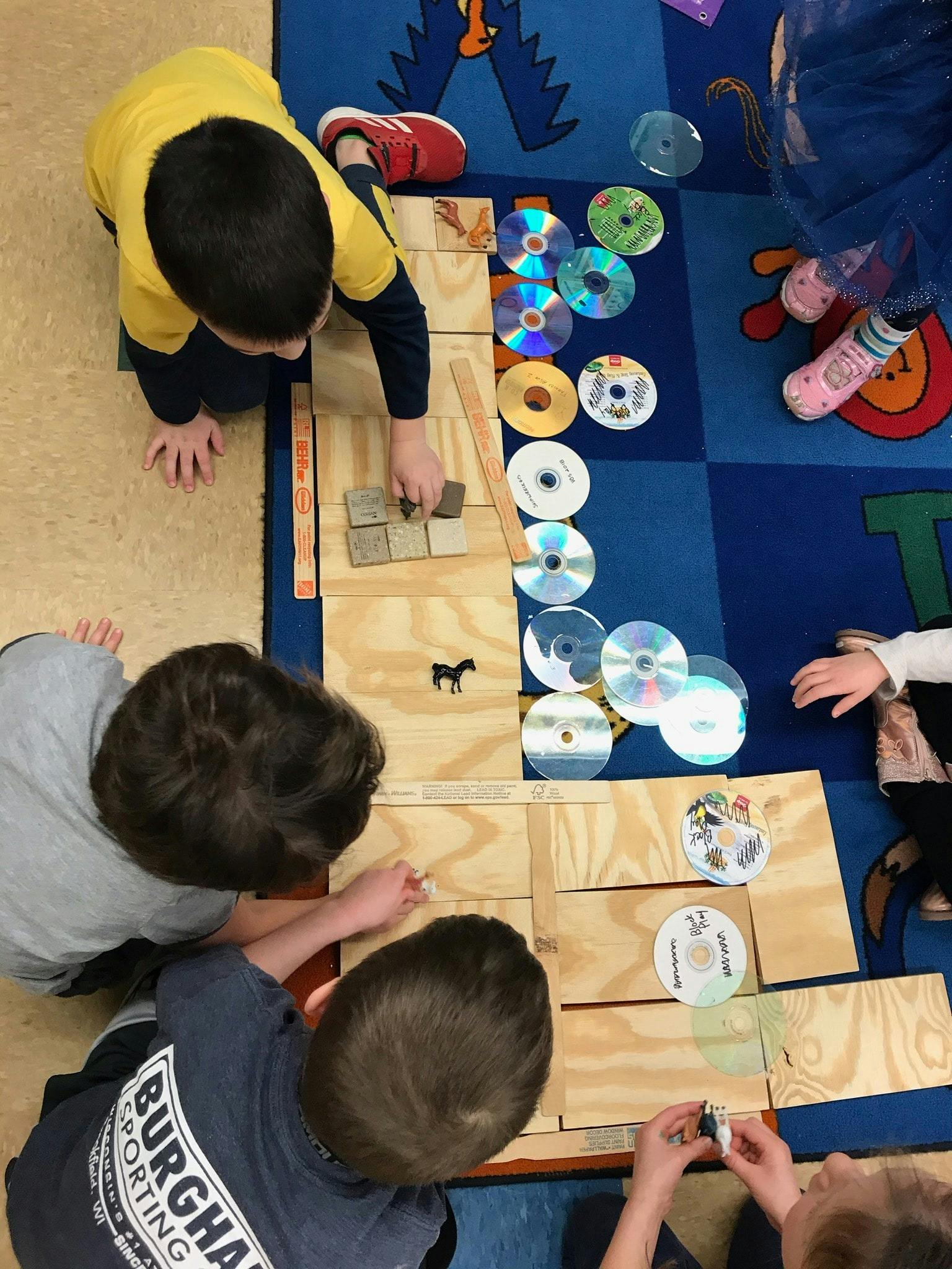 Children playing with wooden blocks and CDs on a rug