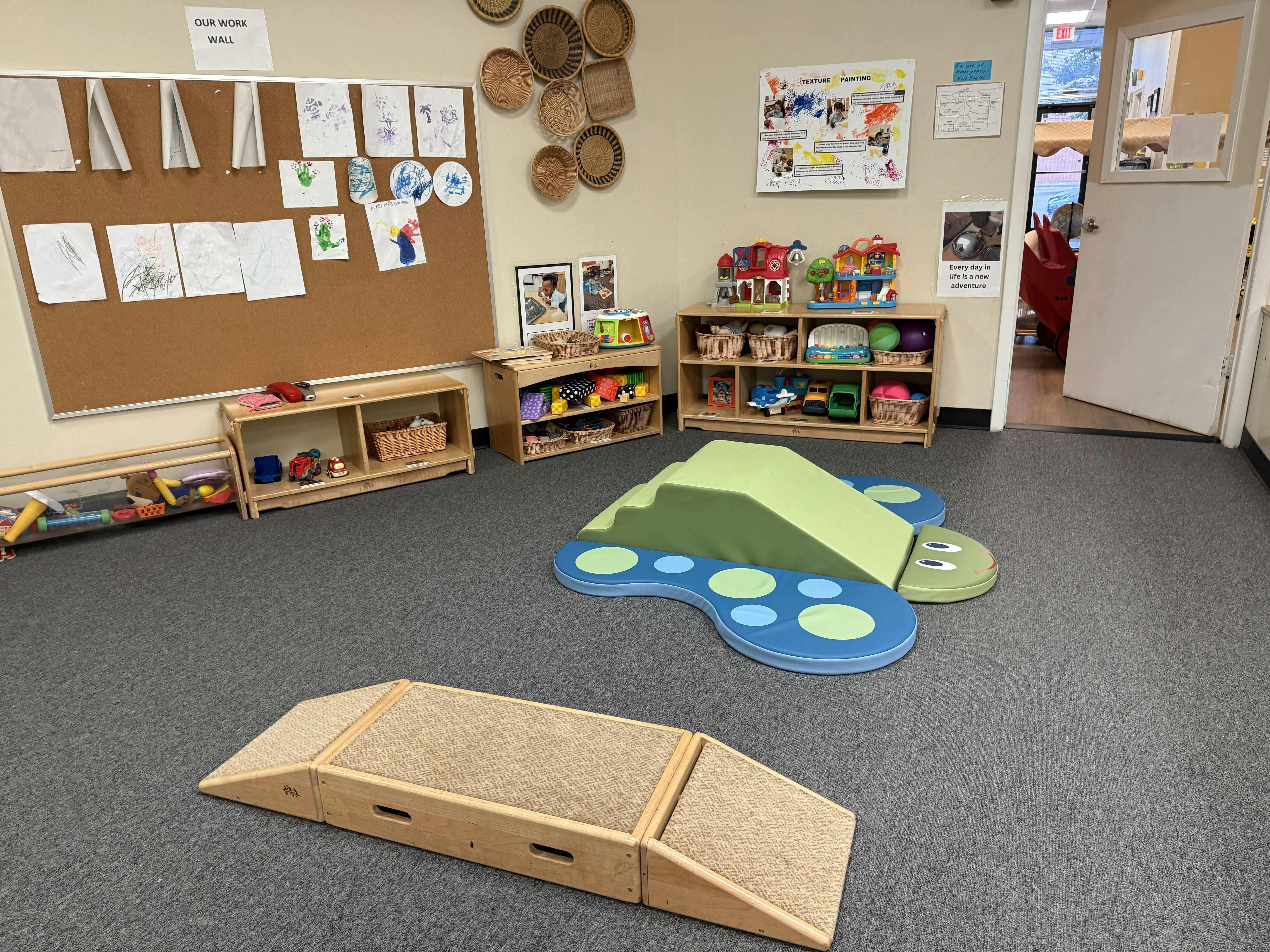 Playroom with soft play equipment, shelves of toys, and a bulletin board