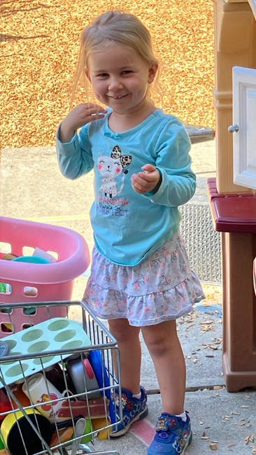 Child standing next to a toy shopping cart