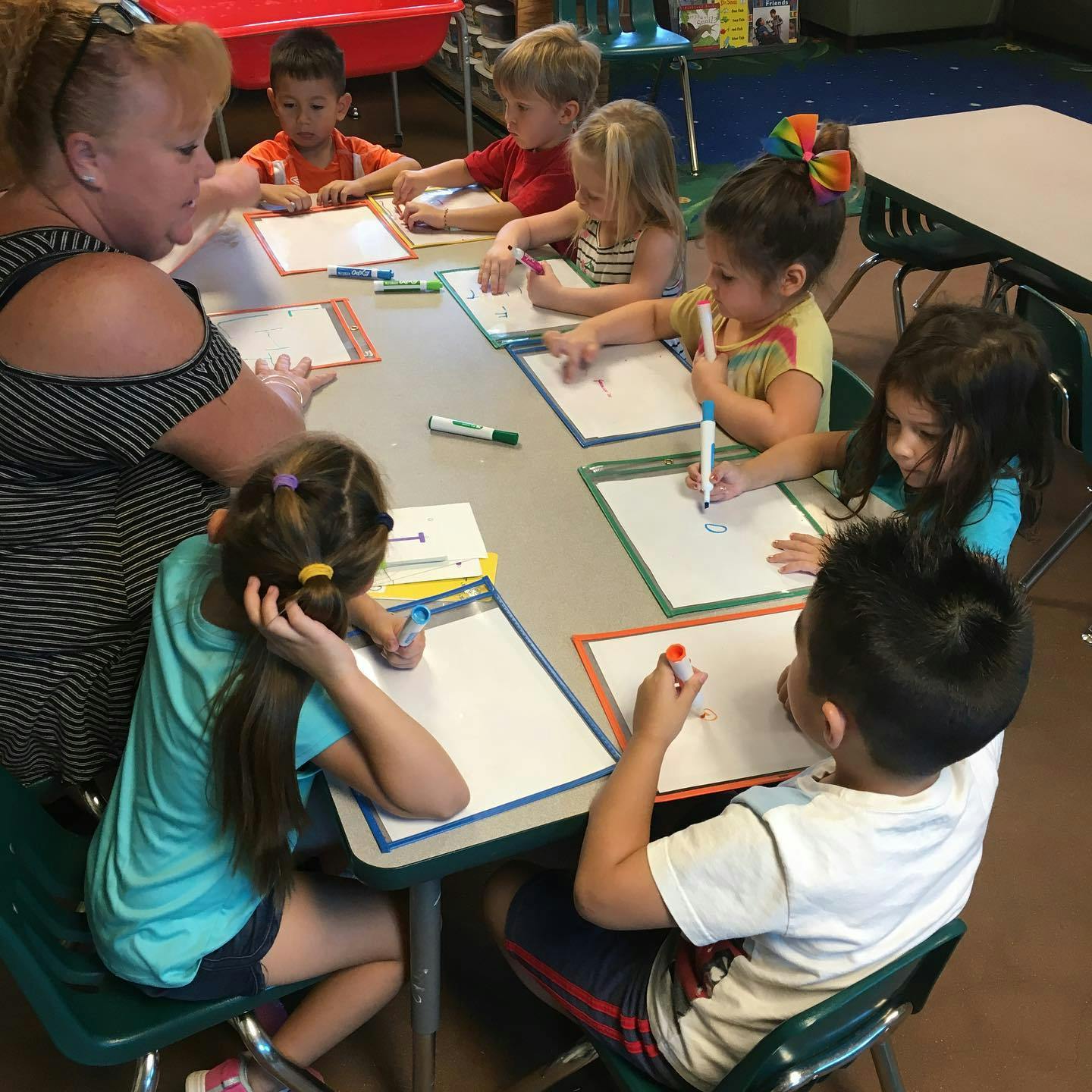 Adult and children drawing on whiteboards at a table