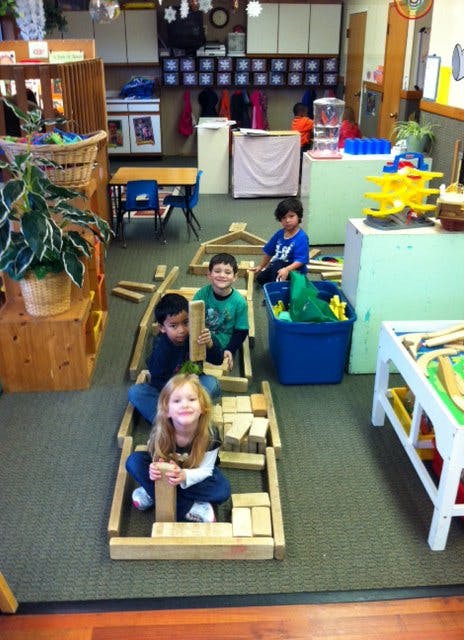 Children playing with wooden blocks in a classroom